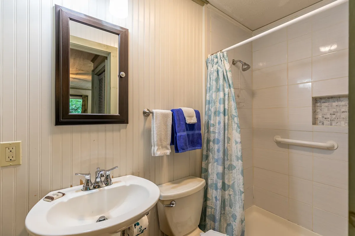 A well-appointed bathroom featuring a modern sink, mirror, spacious shower area, and neatly arranged towels, evoking an atmosphere of spa-like relaxation and daily comfort.